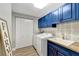 Bright laundry room features blue cabinets, modern tile backsplash, and a convenient utility sink at 501 Haben Blvd # 506, Palmetto, FL 34221