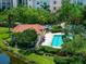 Aerial view of a community pool surrounded by trees and shrubs and neighboring buildings and landscaping at 5420 Eagles Point Cir # 106, Sarasota, FL 34231