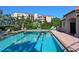 A community pool surrounded by trees, lounge chairs and building is reflecting the clear blue water at 5420 Eagles Point Cir # 106, Sarasota, FL 34231