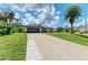 Beautiful exterior view of the home with a well-maintained lawn and a long driveway and blue skies at 5482 Globe Ter, North Port, FL 34286