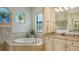Bright bathroom showcasing soaking tub, arched window, and granite countertop at 5622 Arnie Loop, Lakewood Ranch, FL 34211