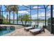 Screened-in pool area overlooking a serene lake with two lounge chairs offering an outdoor oasis at 5622 Arnie Loop, Lakewood Ranch, FL 34211