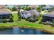 Backyard aerial view of a well-manicured lawn, mature trees, screened-in pool and lake views at 5622 Arnie Loop, Lakewood Ranch, FL 34211