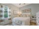 Well-lit bedroom is styled with neutral colors, crisp white linens and warm wood accents at 5622 Arnie Loop, Lakewood Ranch, FL 34211