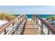 Scenic boardwalk leading to a beautiful sandy beach with turquoise waters and clear sky at 5718 Title Row Dr, Bradenton, FL 34210
