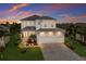 Elegant two-story home showcasing a lush, manicured lawn, paver driveway and vibrant sunset backdrop at 5718 Title Row Dr, Bradenton, FL 34210