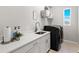 Modern laundry room featuring white cabinets, countertop, stainless sink, and black washer/dryer at 5718 Title Row Dr, Bradenton, FL 34210