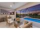 Covered patio with comfortable seating, outdoor kitchen, and a stunning view of the pool and pond at 5718 Title Row Dr, Bradenton, FL 34210