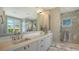 Bathroom with white cabinets, double sinks, and a glass shower with marble walls at 612 Mourning Dove Dr, Sarasota, FL 34236