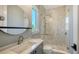 Bathroom with vertical tile in shower, under-sink storage, and large round mirror at 612 Mourning Dove Dr, Sarasota, FL 34236