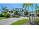 Elegant home with manicured lawn, mature trees, a circular paver driveway, and professionally installed landscaping at 612 Mourning Dove Dr, Sarasota, FL 34236