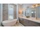 Bright bathroom features a freestanding tub, double vanity, chandelier and textured accent wall at 630 De Narvaez Dr, Longboat Key, FL 34228