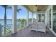 Outdoor seating area on a beautiful deck with white wicker sofas and tables offering an inviting place to relax and enjoy serene water views at 630 De Narvaez Dr, Longboat Key, FL 34228