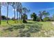 Open backyard with grass, trees, and a clear blue sky at 645 Liberty St, Englewood, FL 34223