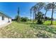 View of the backyard with grass, trees, and the side of the house at 645 Liberty St, Englewood, FL 34223