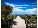 Inviting sandy path with wooden bench leading to a beautiful beach under a bright blue, cloudy sky at 645 Liberty St, Englewood, FL 34223