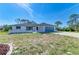 Inviting single-story home with a two-car garage, red front door, and lush surroundings at 645 Liberty St, Englewood, FL 34223