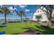 Vibrant outdoor area featuring a large grassy lawn, palm trees, string lights, and lake views at 6990 Richardson Rd, Sarasota, FL 34240