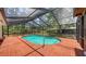 Outdoor pool surrounded by brick and enclosed by a screen, set amongst the trees at 6990 Richardson Rd, Sarasota, FL 34240