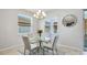 Bright dining area features a glass table, neutral chairs, decorative chandelier, and natural light from two windows at 7379 47Th Avenue E Cir, Bradenton, FL 34203