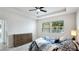 This primary bedroom features a ceiling fan, dresser, and a large window providing natural light at 7379 47Th Avenue E Cir, Bradenton, FL 34203