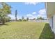 Large backyard with green grass and white vinyl fence on a sunny day at 7595 Berwick St, North Port, FL 34287