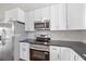 Stylish kitchen with stainless steel appliances, white cabinetry, and dark countertops at 7595 Berwick St, North Port, FL 34287