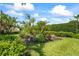 Tranquil backyard with a curated tropical garden, showcasing diverse plant life and well-maintained green grass at 7716 Uliva Way, Sarasota, FL 34238