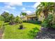 Inviting backyard featuring a well-manicured lawn, tropical foliage, and an elegant home exterior at 7716 Uliva Way, Sarasota, FL 34238