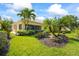 Scenic backyard with mature palms, lush green grass, and a charming screened-in lanai on a sunny day at 7716 Uliva Way, Sarasota, FL 34238