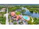 Aerial view of a community center with a resort-style pool, tennis courts, parking area, and access to the lake at 7716 Uliva Way, Sarasota, FL 34238