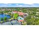 Beautiful aerial view showcases community center, pool, tennis courts, and lush landscaping near a tranquil lake at 7716 Uliva Way, Sarasota, FL 34238