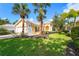Charming single-story home featuring a tile roof, lush landscaping, and mature palm trees in a well-maintained front yard at 7716 Uliva Way, Sarasota, FL 34238