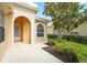 Inviting front porch featuring an arched entryway, manicured landscaping, and a charming residential facade at 7716 Uliva Way, Sarasota, FL 34238