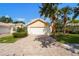 Home featuring a two-car garage with brick driveway, complemented by tropical landscaping and a tile roof at 7716 Uliva Way, Sarasota, FL 34238