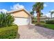 Home with a two-car garage and brick driveway, accented by lush landscaping and mature palm trees at 7716 Uliva Way, Sarasota, FL 34238