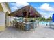 Pool bar with thatched roof, barstools, a TV, and access to the pool area at 7716 Uliva Way, Sarasota, FL 34238