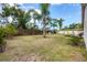 Spacious backyard with lush grass, palm trees, and a partial fence at 7834 38Th E Ct, Sarasota, FL 34243