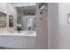 Bright bathroom featuring double sinks, white cabinets, decorative mirrors, and walk-in shower with tiled walls at 8706 52Nd E Dr, Bradenton, FL 34211