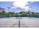An outdoor tennis court is shown with lighting and a covered rest area for players at 8706 52Nd E Dr, Bradenton, FL 34211