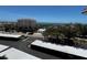 View from a balcony overlooking a street with a car, buildings and the ocean in the distance at 8977 Midnight Pass Rd # 521, Sarasota, FL 34242