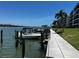 Community dock with boat, green grass, and condo buildings under a clear blue sky at 8977 Midnight Pass Rd # 521, Sarasota, FL 34242