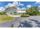 View of the home exterior with a circular driveway, green awning, and lush surrounding greenery at 919 Palm View Way, Sarasota, FL 34240