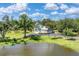 Charming home featuring a lush green lawn, mature trees, and a serene pond on a sunny day at 919 Palm View Way, Sarasota, FL 34240
