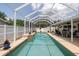 A sparkling pool with a screen enclosure and small water feature, with furniture in the background at 11021 4Th E Ave, Bradenton, FL 34212