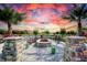 Inviting fire pit area with comfortable seating, set against a scenic backdrop of palm trees and a serene lake at 11427 Viani Ter, Palmetto, FL 34221