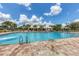 Large community pool with ample lounge seating offers a refreshing escape with mature palm trees and clear blue skies at 12755 Rainwashed Loop, Parrish, FL 34219