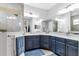 Main bathroom with dual sinks, granite countertops, blue cabinets, and a glass enclosed shower at 12755 Rainwashed Loop, Parrish, FL 34219