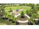 Aerial shot of a neighborhood playground with swings, a slide, and shaded seating, surrounded by palm trees at 13819 American Prairie Pl, Bradenton, FL 34211