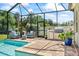 Backyard pool with covered grill area and seating surrounded by lush landscaping at 13819 American Prairie Pl, Bradenton, FL 34211